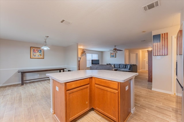 kitchen featuring ceiling fan, a kitchen island, light wood-type flooring, and hanging light fixtures