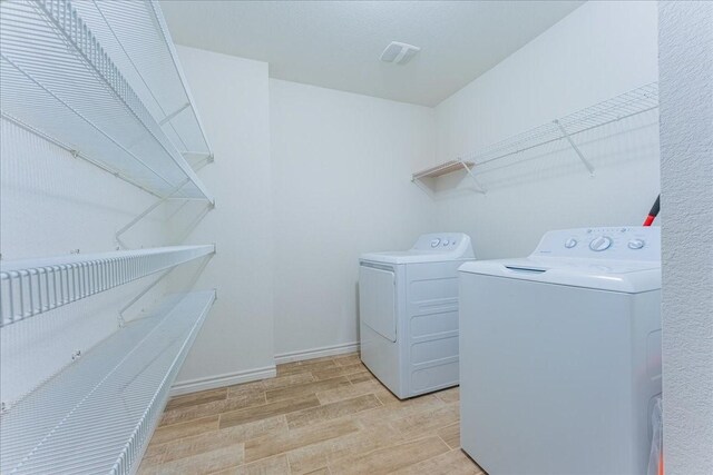 clothes washing area with light wood-type flooring and washer and clothes dryer