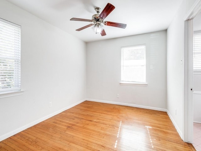 empty room featuring ceiling fan, a healthy amount of sunlight, and light hardwood / wood-style flooring