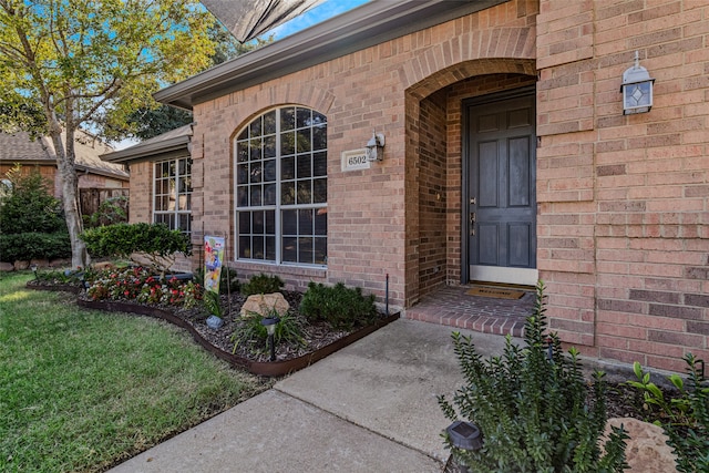 view of exterior entry featuring a lawn