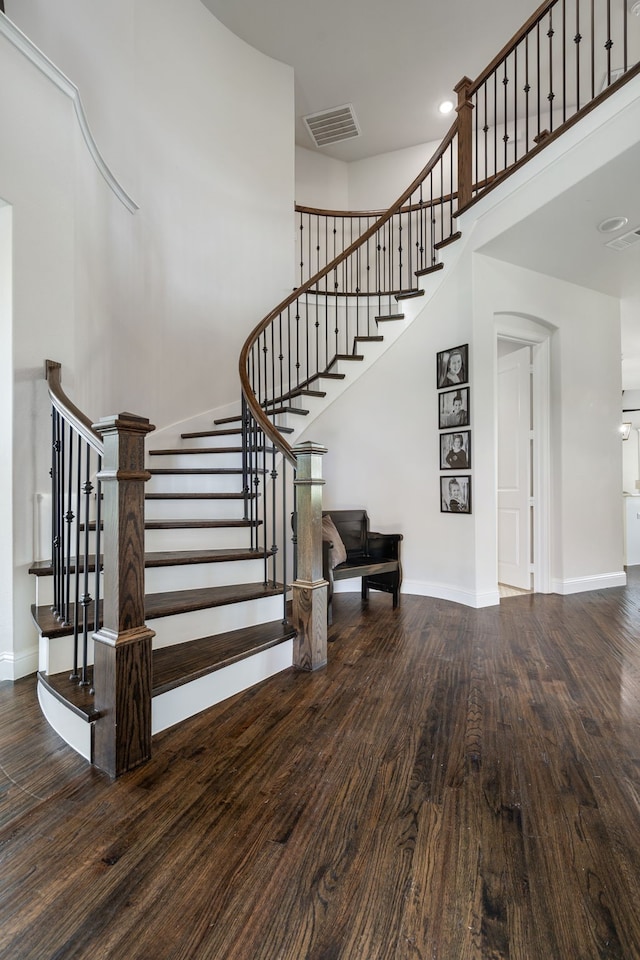 stairway featuring wood-type flooring and a high ceiling