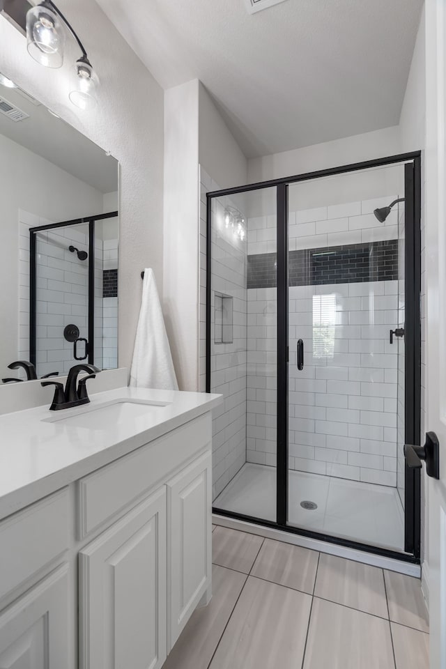 bathroom featuring tile patterned floors, vanity, and a shower with shower door