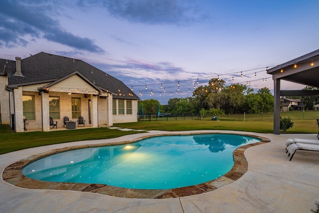 pool at dusk with a yard and a patio area