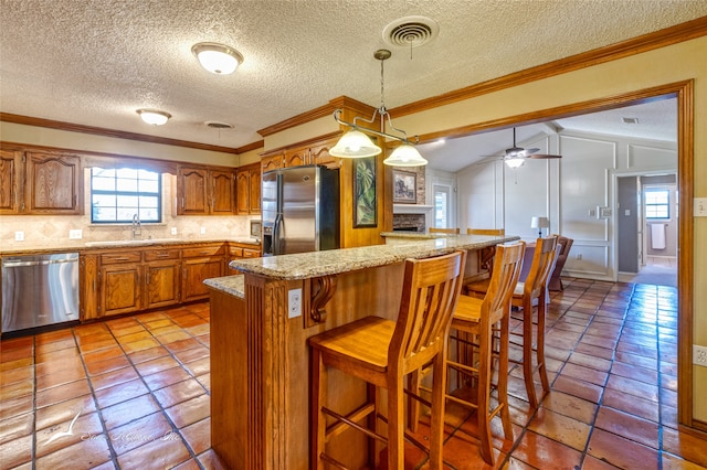 kitchen featuring appliances with stainless steel finishes, ornamental molding, a textured ceiling, vaulted ceiling, and sink