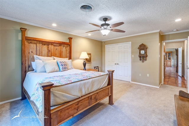 bedroom with ceiling fan, carpet floors, a textured ceiling, a closet, and ornamental molding