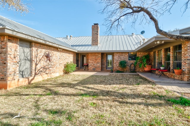 rear view of property with a lawn and a patio area