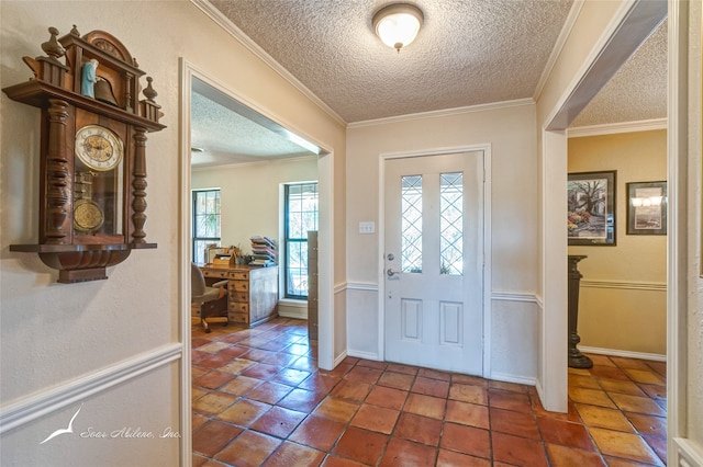 foyer entrance with built in desk, a textured ceiling, dark tile patterned flooring, and ornamental molding