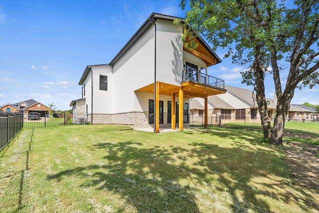 back of property featuring a balcony and a lawn