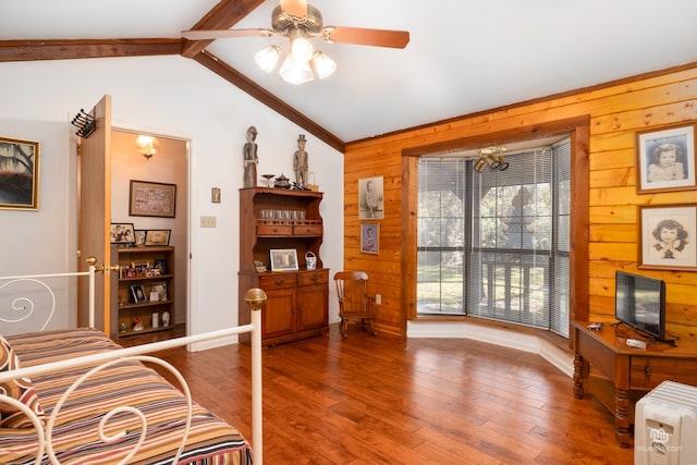 sitting room with wood-type flooring, lofted ceiling with beams, wooden walls, and ceiling fan