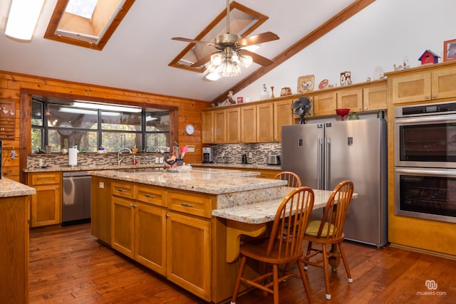 kitchen with light stone counters, dark hardwood / wood-style flooring, a kitchen island, and stainless steel appliances