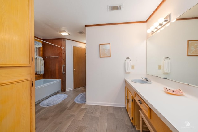 bathroom with shower / bath combination, crown molding, hardwood / wood-style floors, and vanity