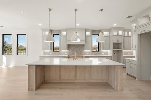 kitchen with backsplash, a large island, sink, and white cabinets