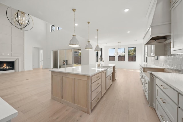 kitchen with a spacious island, decorative light fixtures, sink, and backsplash