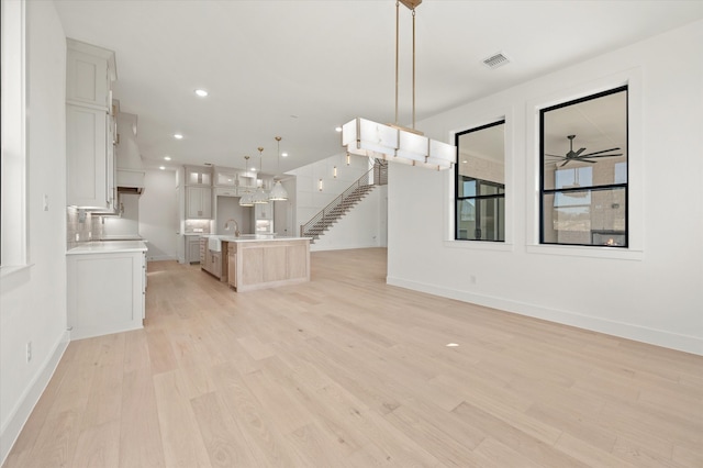 unfurnished living room with ceiling fan, sink, and light hardwood / wood-style flooring