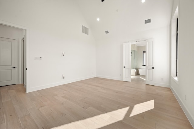 spare room with light hardwood / wood-style floors and high vaulted ceiling