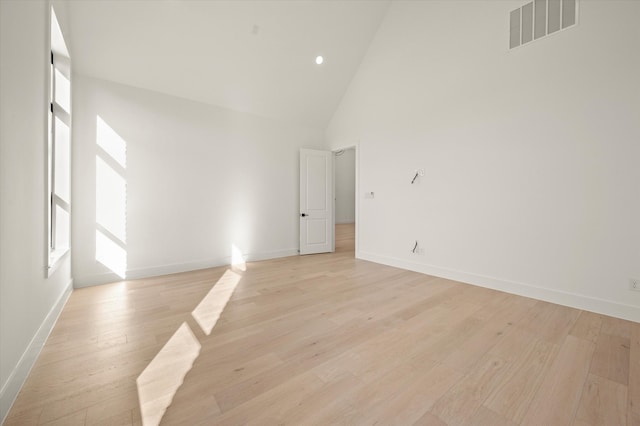 spare room featuring light hardwood / wood-style flooring, high vaulted ceiling, and a healthy amount of sunlight