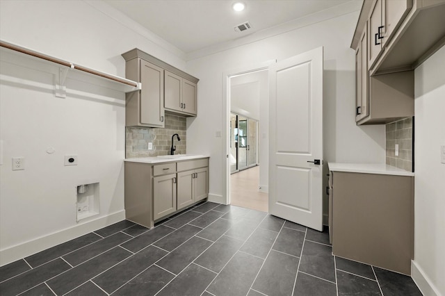 kitchen featuring tasteful backsplash, ornamental molding, gray cabinets, and sink