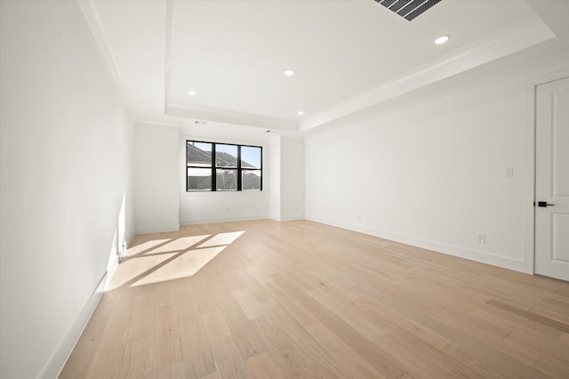 unfurnished room with a raised ceiling, crown molding, and light hardwood / wood-style flooring