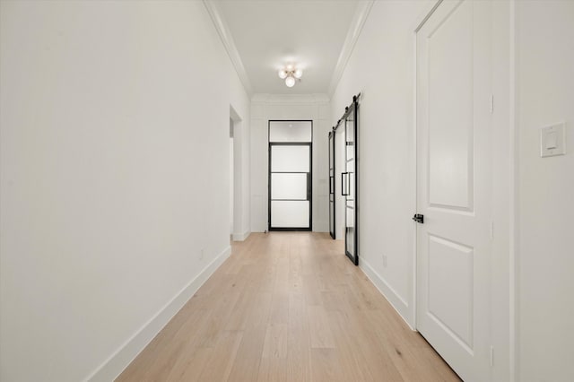 hall with crown molding, light hardwood / wood-style flooring, and a barn door