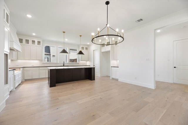 kitchen with a center island, hanging light fixtures, light hardwood / wood-style floors, white cabinetry, and a chandelier