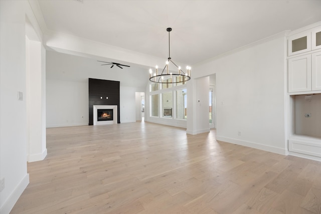 unfurnished living room featuring ceiling fan with notable chandelier, a large fireplace, light wood-type flooring, and crown molding