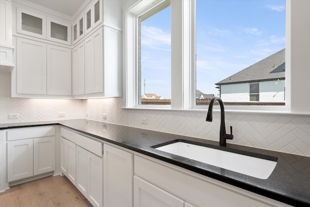 kitchen with white cabinetry, sink, a healthy amount of sunlight, and light hardwood / wood-style floors