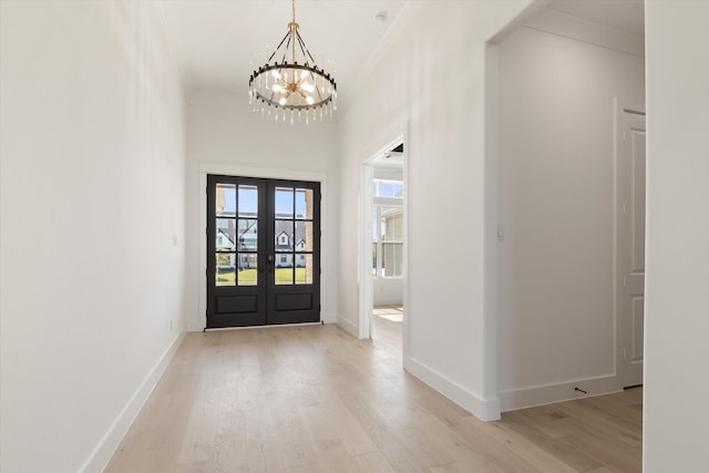 foyer featuring ornamental molding, french doors, a chandelier, and light wood-type flooring