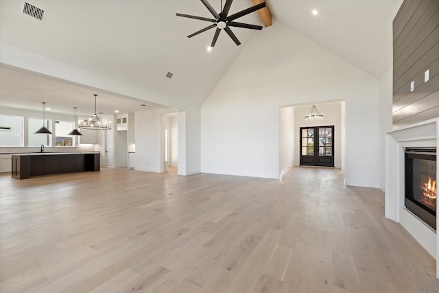 unfurnished living room featuring ceiling fan, beam ceiling, high vaulted ceiling, and light hardwood / wood-style flooring