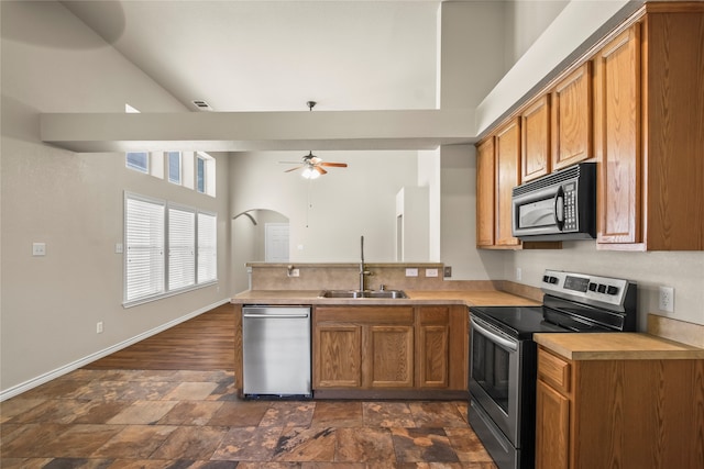 kitchen featuring ceiling fan, sink, stainless steel appliances, a high ceiling, and kitchen peninsula