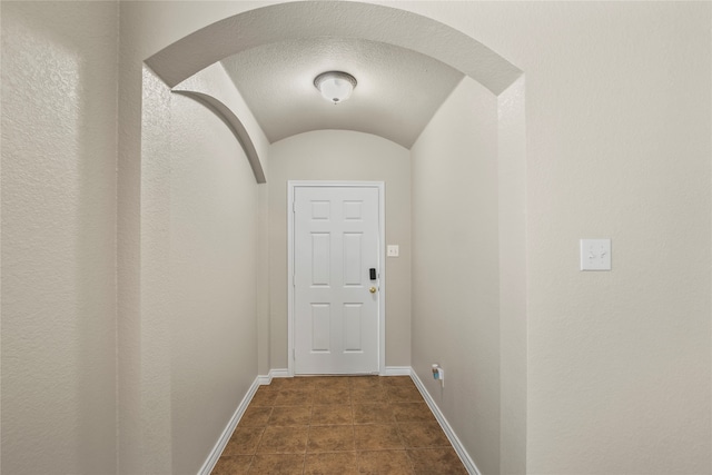 doorway with a textured ceiling and dark tile patterned floors