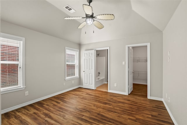 unfurnished bedroom featuring a walk in closet, ceiling fan, dark hardwood / wood-style flooring, and multiple windows