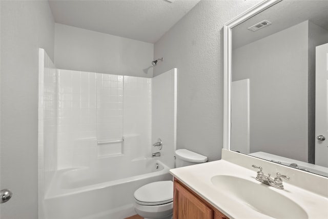 full bathroom featuring vanity, washtub / shower combination, a textured ceiling, and toilet