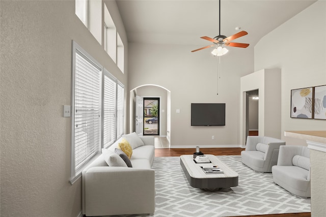 living room featuring ceiling fan, high vaulted ceiling, and wood-type flooring