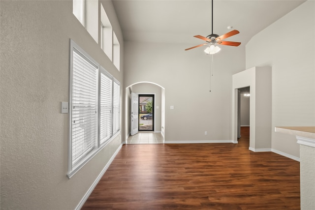 unfurnished living room featuring dark hardwood / wood-style flooring, high vaulted ceiling, and ceiling fan