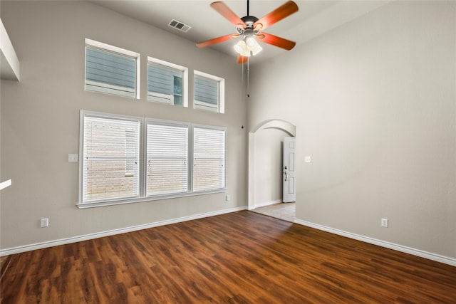 unfurnished room with ceiling fan, hardwood / wood-style floors, and a towering ceiling