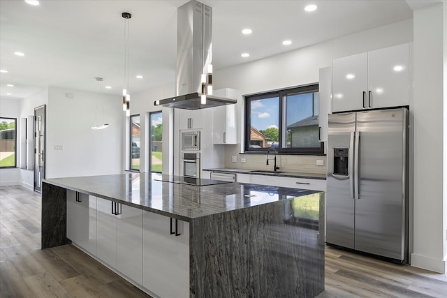 kitchen featuring sink, appliances with stainless steel finishes, hanging light fixtures, island range hood, and white cabinets