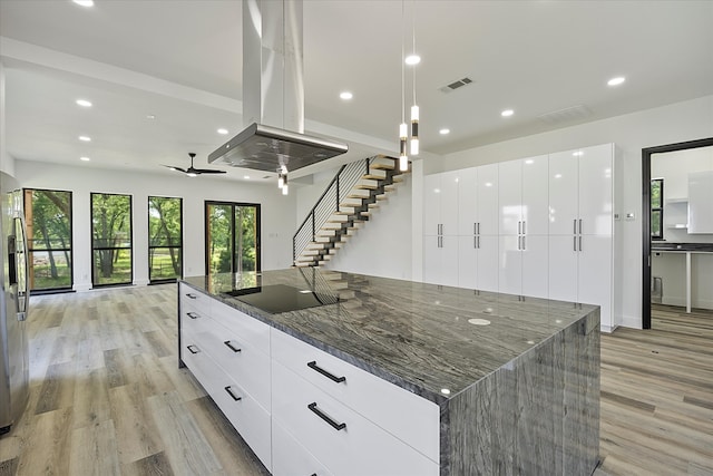 kitchen featuring island range hood, white cabinets, dark stone counters, a large island, and black electric stovetop