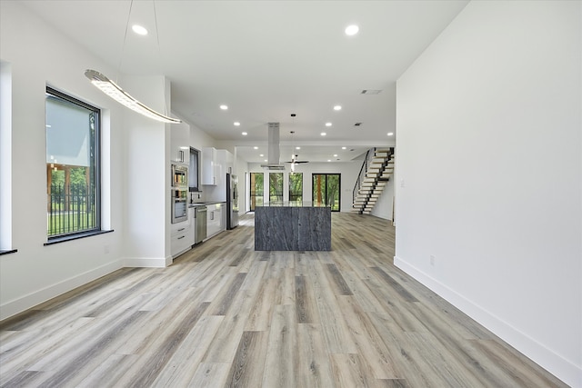 unfurnished living room featuring a wealth of natural light and light wood-type flooring