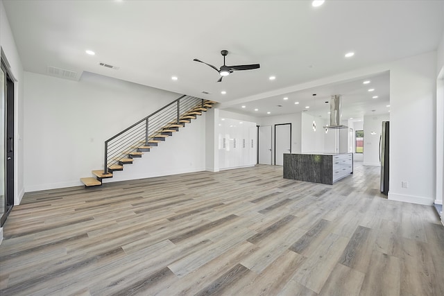 unfurnished living room featuring ceiling fan and light hardwood / wood-style floors