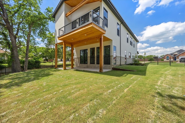 back of property featuring a balcony, a lawn, and a patio area