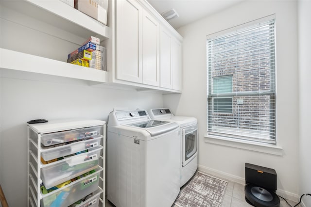 clothes washing area featuring cabinets, light tile patterned flooring, and washing machine and dryer