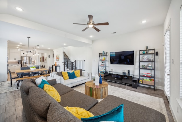 living room with hardwood / wood-style floors and ceiling fan with notable chandelier