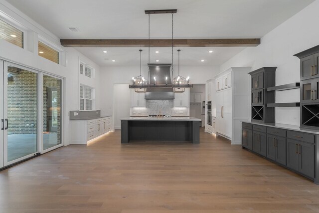 unfurnished living room featuring a tiled fireplace, ceiling fan, beamed ceiling, and light wood-type flooring