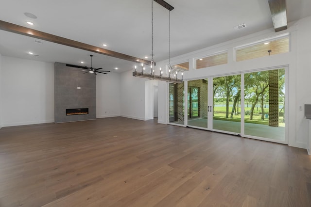 unfurnished living room with beam ceiling, ceiling fan, a fireplace, and hardwood / wood-style flooring