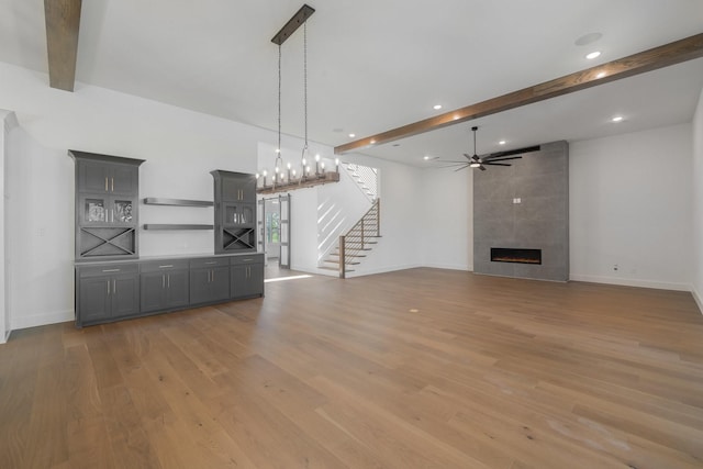 unfurnished living room with beamed ceiling, a fireplace, and light hardwood / wood-style flooring