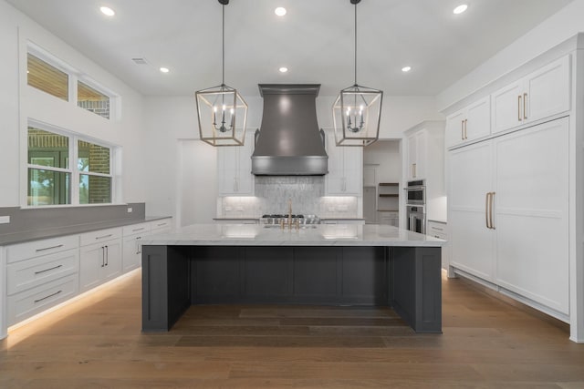 kitchen featuring pendant lighting, custom exhaust hood, white cabinets, dark hardwood / wood-style floors, and a large island