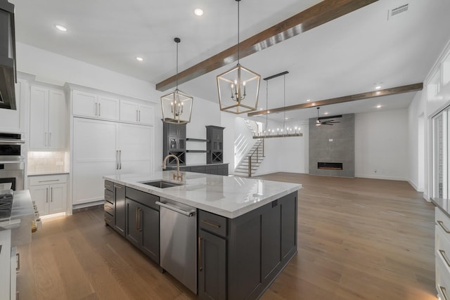 kitchen with dishwasher, sink, ceiling fan, a fireplace, and white cabinetry