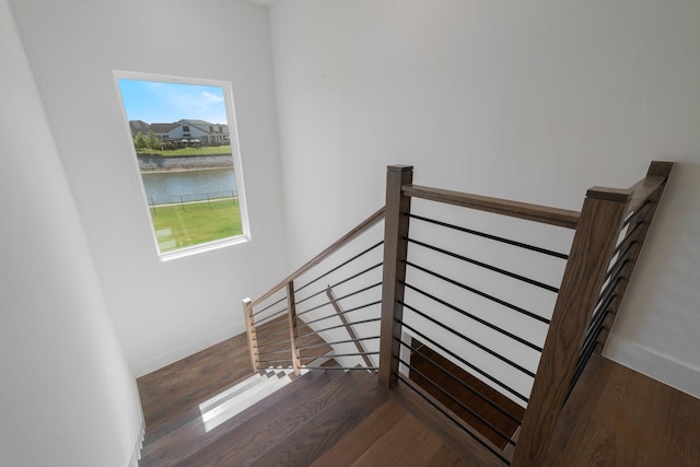 staircase featuring wood-type flooring and a water view