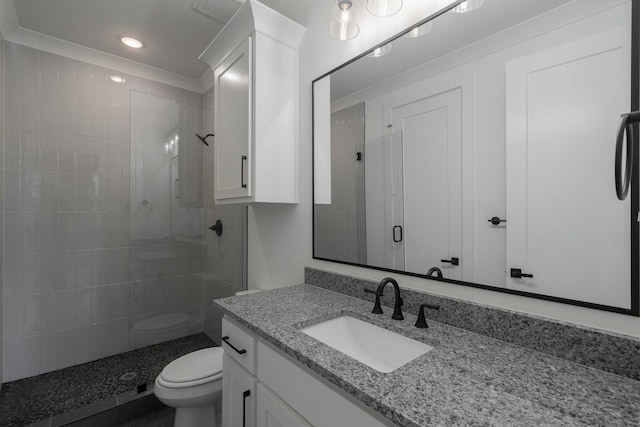 bathroom featuring vanity, toilet, a shower with door, and ornamental molding