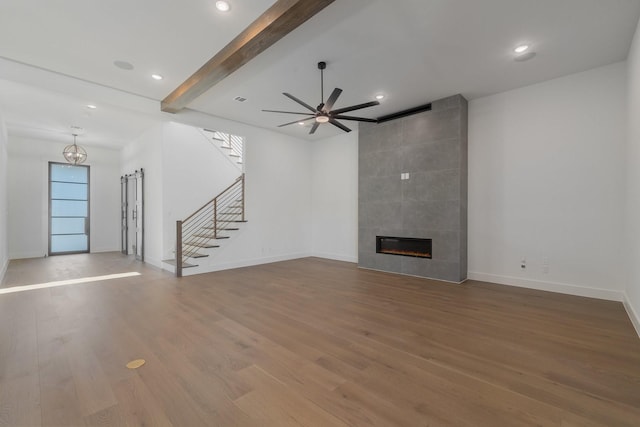 unfurnished living room with beamed ceiling, hardwood / wood-style floors, ceiling fan, and a tiled fireplace